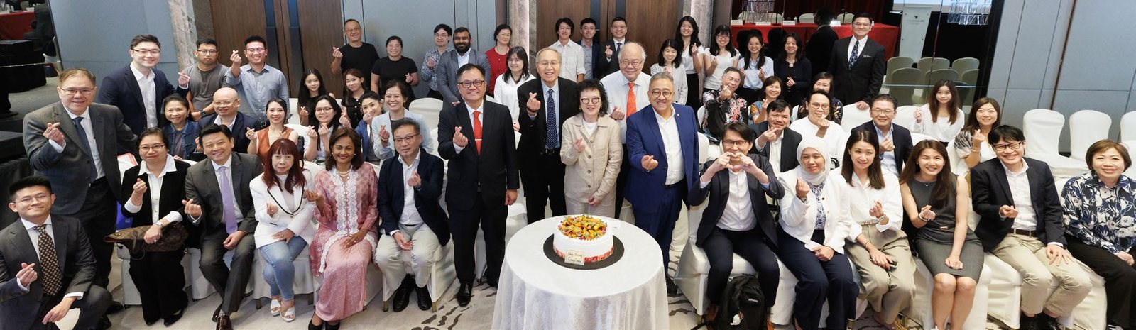 A full room of members around a table with a cake at the 2026 Annual General Meeting