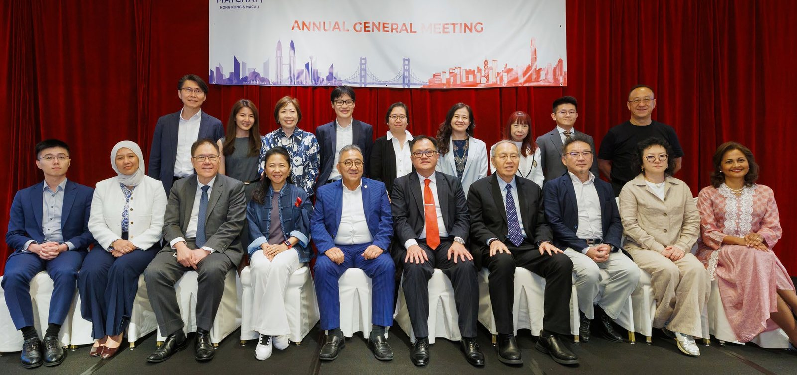 Members seated and standing in two rows under the Annual General Meeting banner at the JW Marriott Hotel Hong Kong