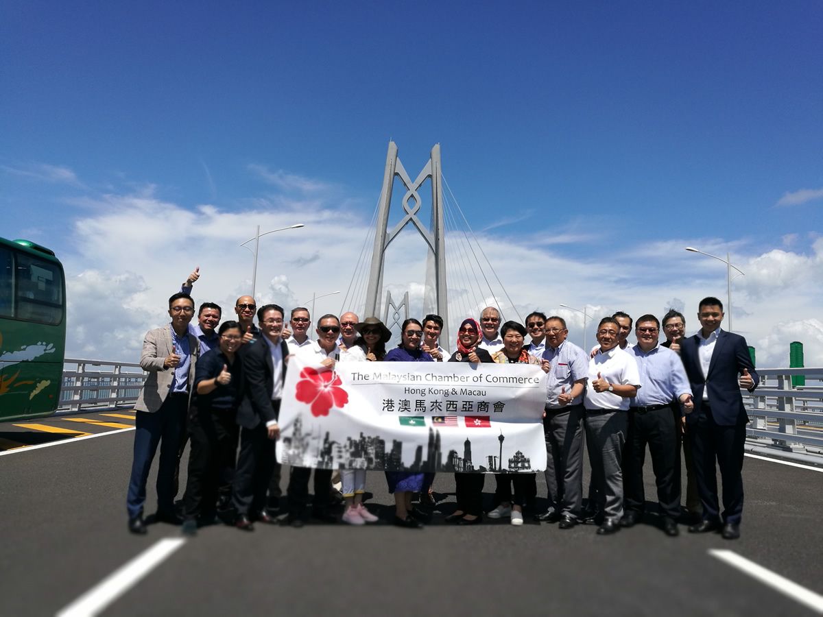 Members holding the MAYCHAM banner in front of a tower of the Hong Kong Zhuhai Macau Bridge