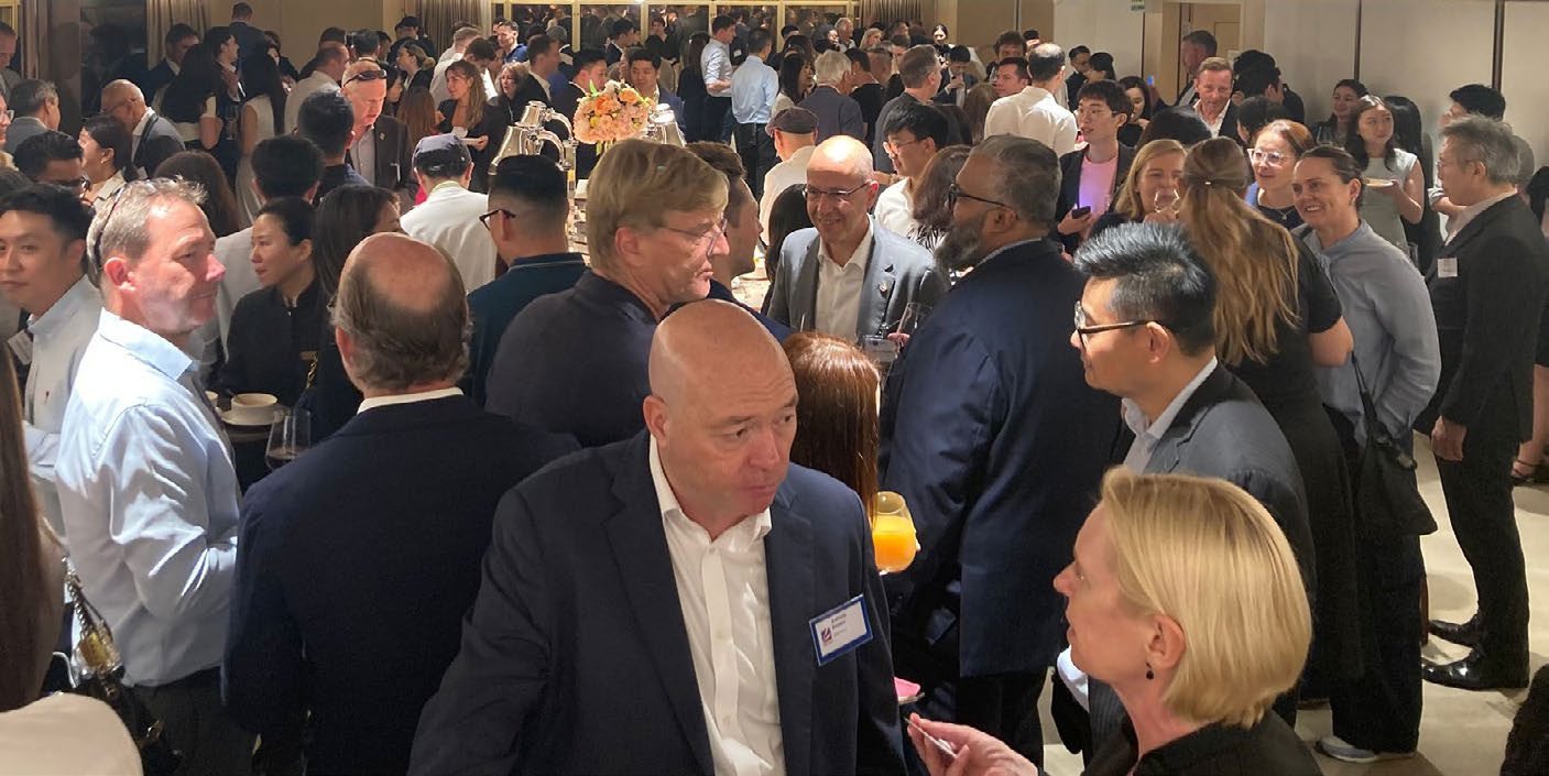 A crowded room of guests with drinks at the InterCham Connecting People Cocktail