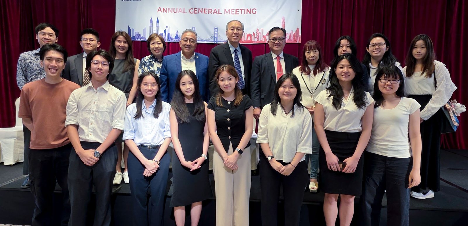 A front row of young people with members of the chamber behind them, under the Annual General Meeting banner